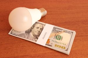 Bundle of dollars with the inscription electricity and energy saving light bulbs. Energy saving concept.