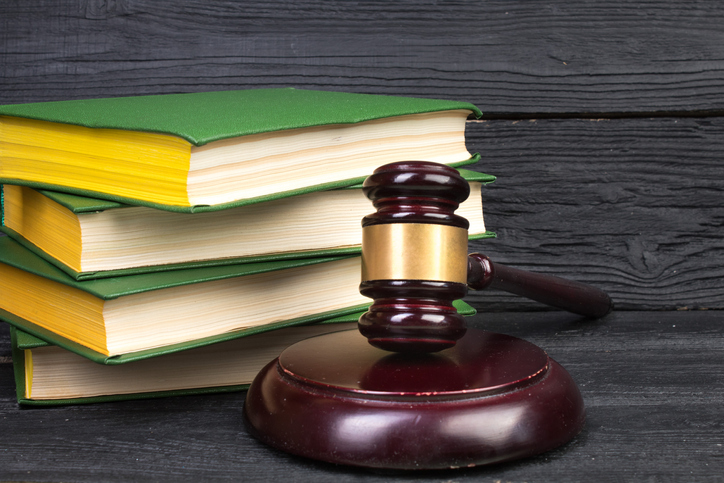 Law concept - Open law book with a wooden judges gavel on table in a courtroom or law enforcement office isolated on white background. Copy space for text.