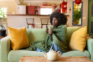 Woman encased in a blanket, with a hot drink