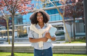 Happy African American girl student walking outside university campus, portrait.