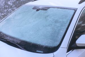 Frozen car windshield covered with ice and snow on a winter day. Close-up view.