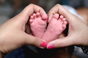 A Close-up of tiny baby feet and mother's hand fingers