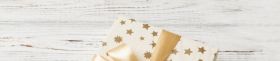 wrapped Christmas or other holiday handmade present in white paper with gold ribbon on colored background. Present box, decoration of gift on colored table, top view with copy space
