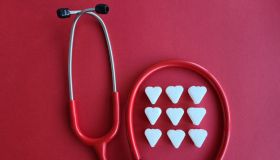 Stethoscope With White Hearts on Red Background