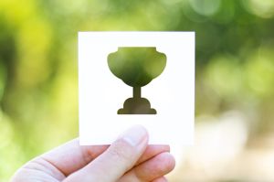 Holding the paper with Trophy Award in front of a beautiful blur nature background