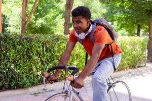 Young delivery man riding bicycle with headphones