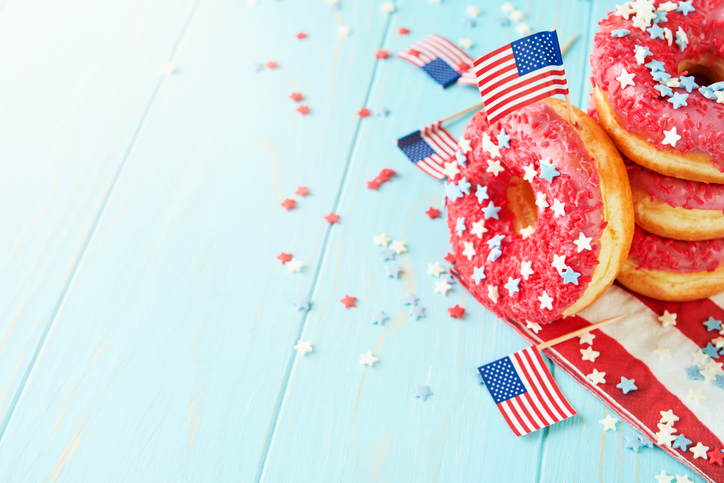Patriotic sweet donuts 4th july with american flag. Delicious american donuts with red icing and blue and red stars toping on blue background. Dessert food for American Independence Day celebration.