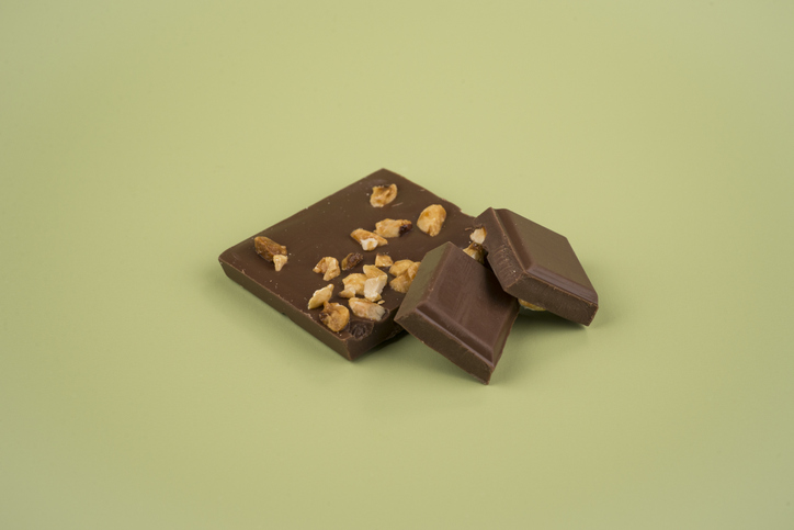 Pieces of milk chocolate with hazelnut on a coloured background