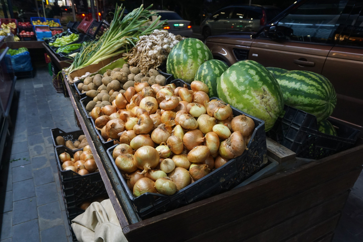 Night fruit and vegetable market. Crates filled with fresh products. Onions, watermelons, green onions, and potatoes.
