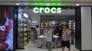 Pedestrians walk past the American footwear company Crocs...