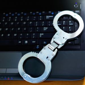 Handcuffs on a laptop represent cyber crime or computer security