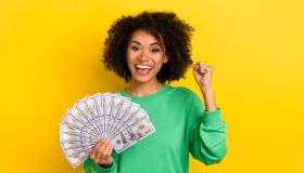 Portrait of delighted overjoyed girl raise fist celebrate success isolated on yellow color background