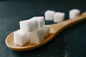 White crystalline sugar cubes on a wooden spoon