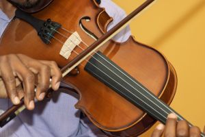 violin close up, african man playing, yellow wall background