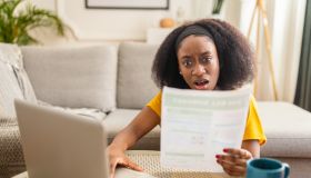 Woman reacting to a bill while working on laptop