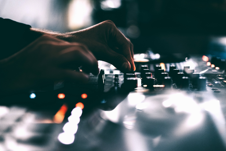 American DJ working with sound, spinning turntable records at a night club party
