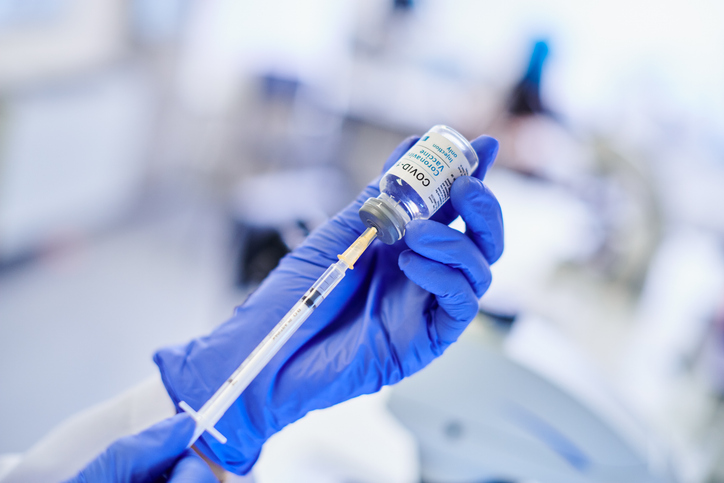 A shot of hands holding up a syringe and vial with the covid-19 vaccine