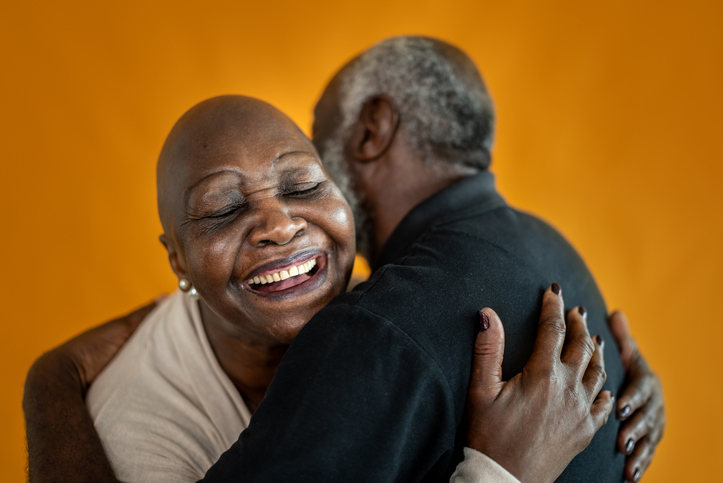 Senior couple embracing in studio shot on an orange background