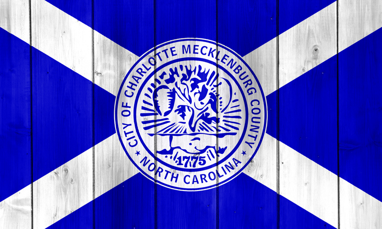 Flag of the city of Charlotte, North Carolina, USA, on a background of a wooden fence. Conceptual collage