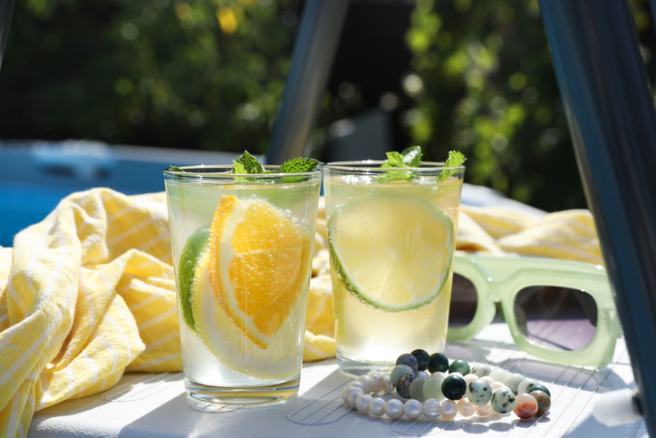 Tasty cocktail in glasses and sunglasses near swimming pool outdoors