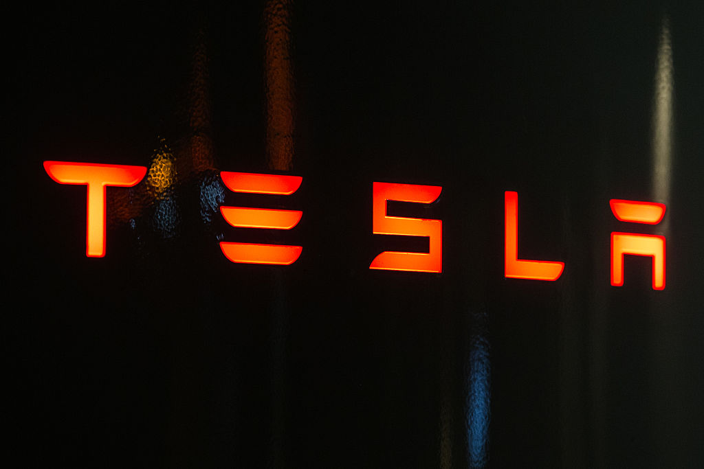 In this photo illustration, the Tesla logo is seen on a...