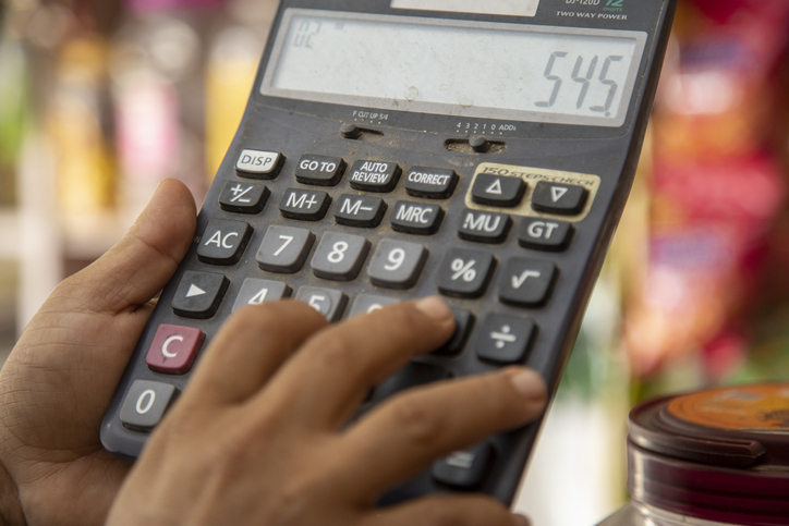 Close-Up of Hands Using Calculator in Colorful Indian Shop Background