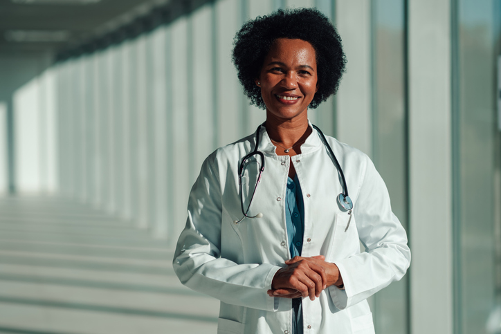 Black woman doctor smiling in hospital corridor