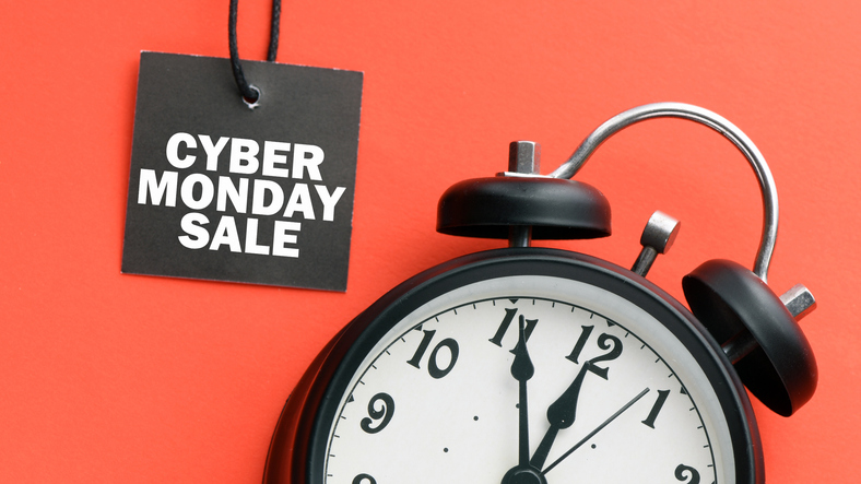 CYBER MONDAY SALE words on a small tag and red background with a clock. View from above.