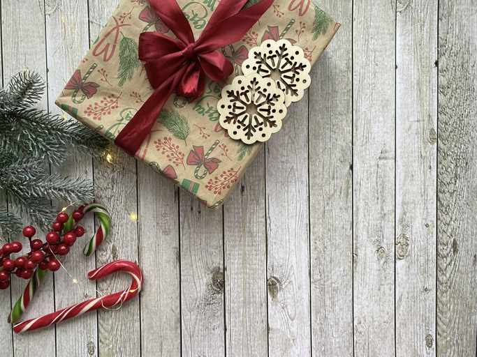 Cozy Christmas setup with a gift and fir greenery on a pale wooden background