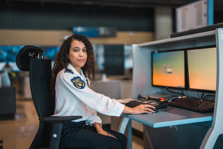 Young Hispanic Female Airport Security Officer Working at Modern Surveillance Desk
