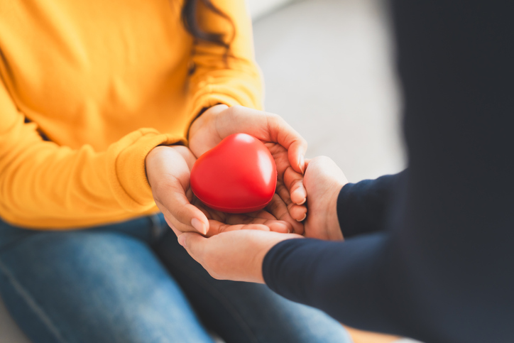 Closeup view of red heart on woman and man hands. Healthy and valentines day concept