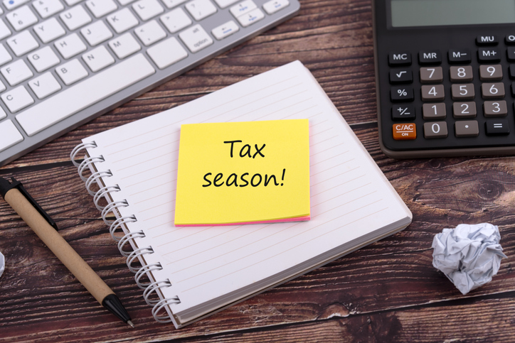 High angle view of notepad and adhesive note with text Tax season