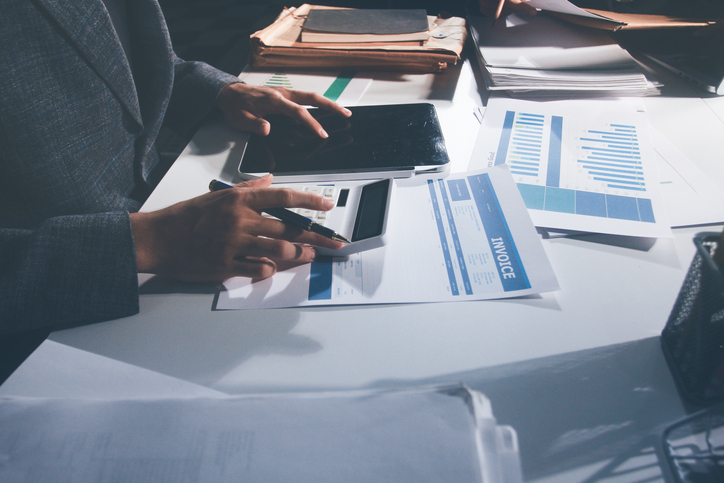 Professional photo of a person's hands reviewing a contract or legal document on a desk, for concepts of business, finance, and legal affairs