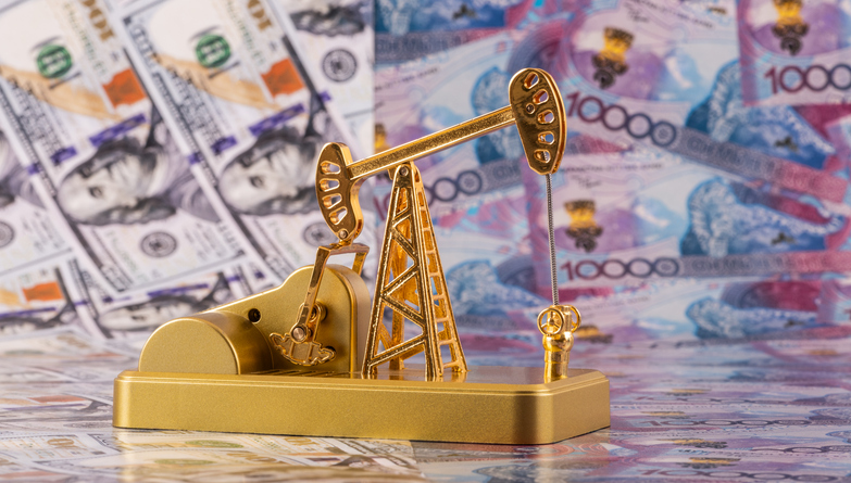 A miniature oil pump against the background of 10,000 Kazakhstani tenge and 100 US dollar bills.