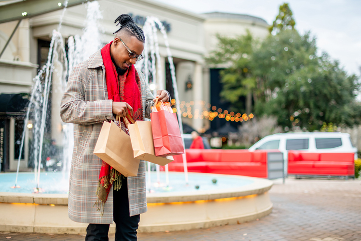 Joyful Male checking bags while shopping