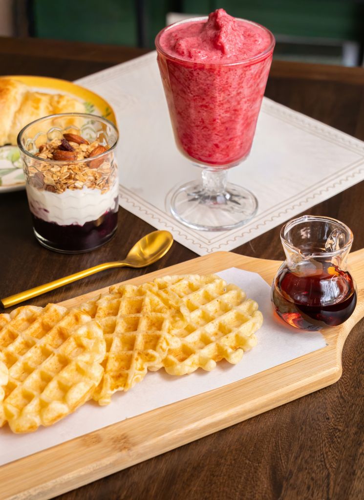 Elegant breakfast table setup with Waffles, Croissant, Yogurt and Smoothie