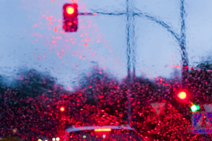 Street view at dusk, raining, red traffic lights, city life.