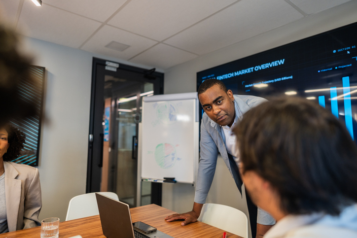 Mid adult leader talking with coworkers during business meeting at office