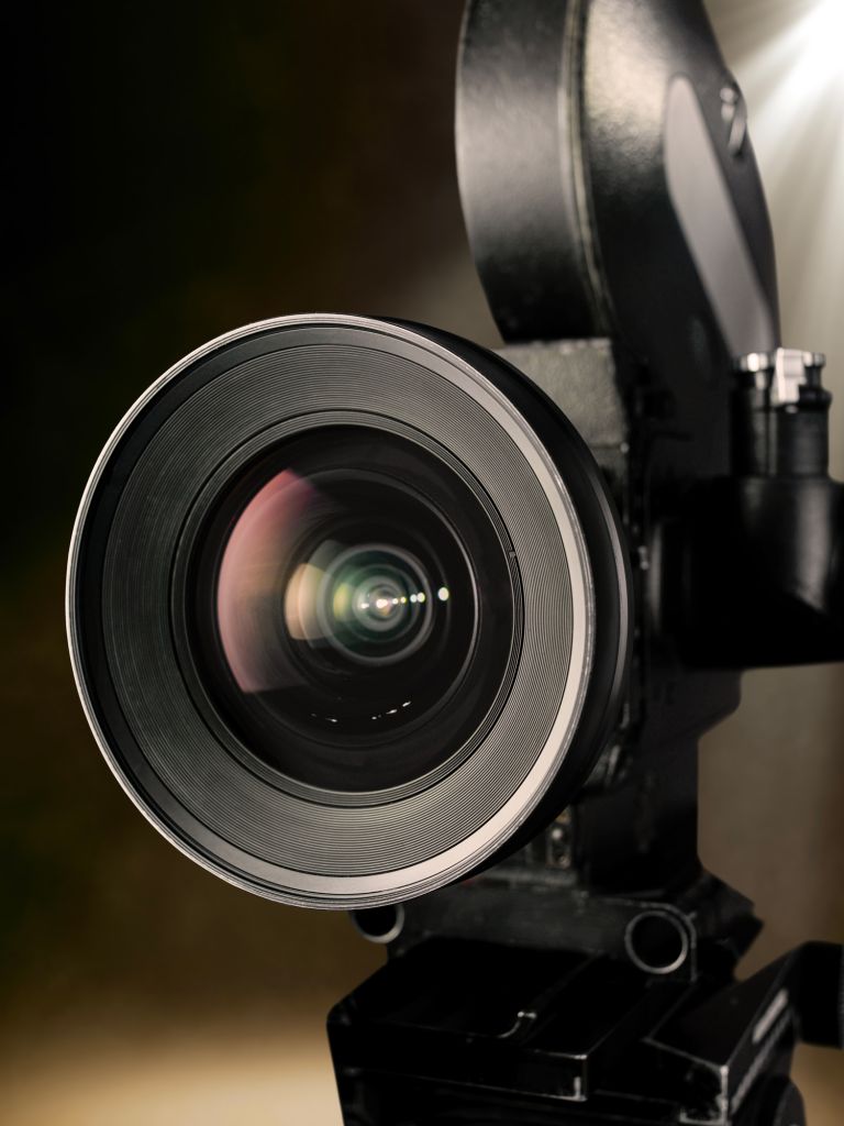 Close up of vintage cinema projector lens with light beam in dark theater
