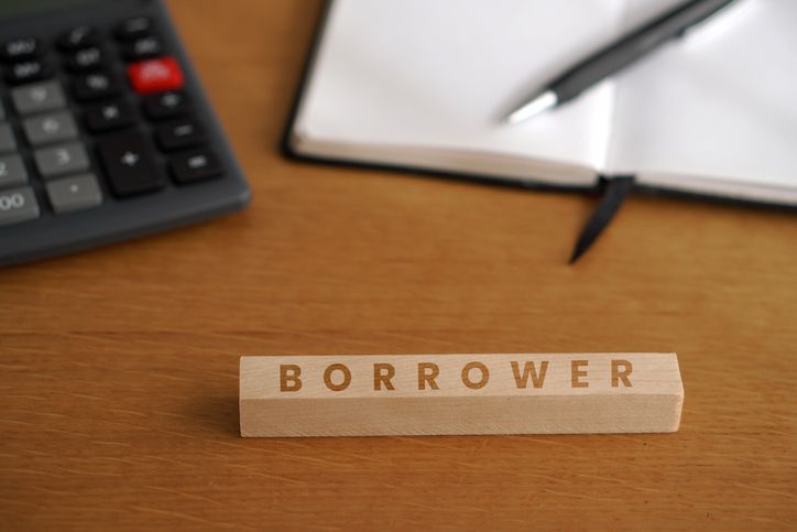 BORROWER. Business and financial concepts. Word written on a wooden block with calculator and notebook in the background